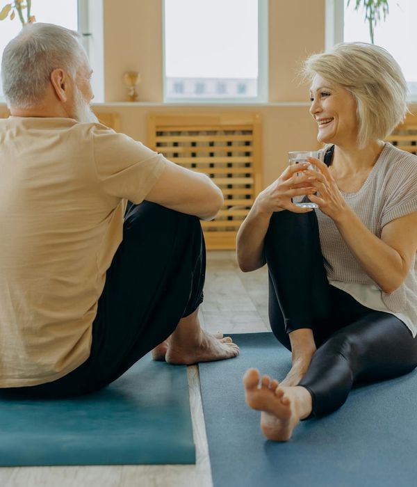 A smiling woman with a yoga mat looking relaxed and happy.